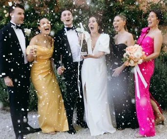 A bridal party pops a bottle of sparkling wine at a wedding in the Hunter Valley, NSW