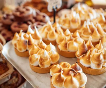 A close up of a tray of lemon meringue pies