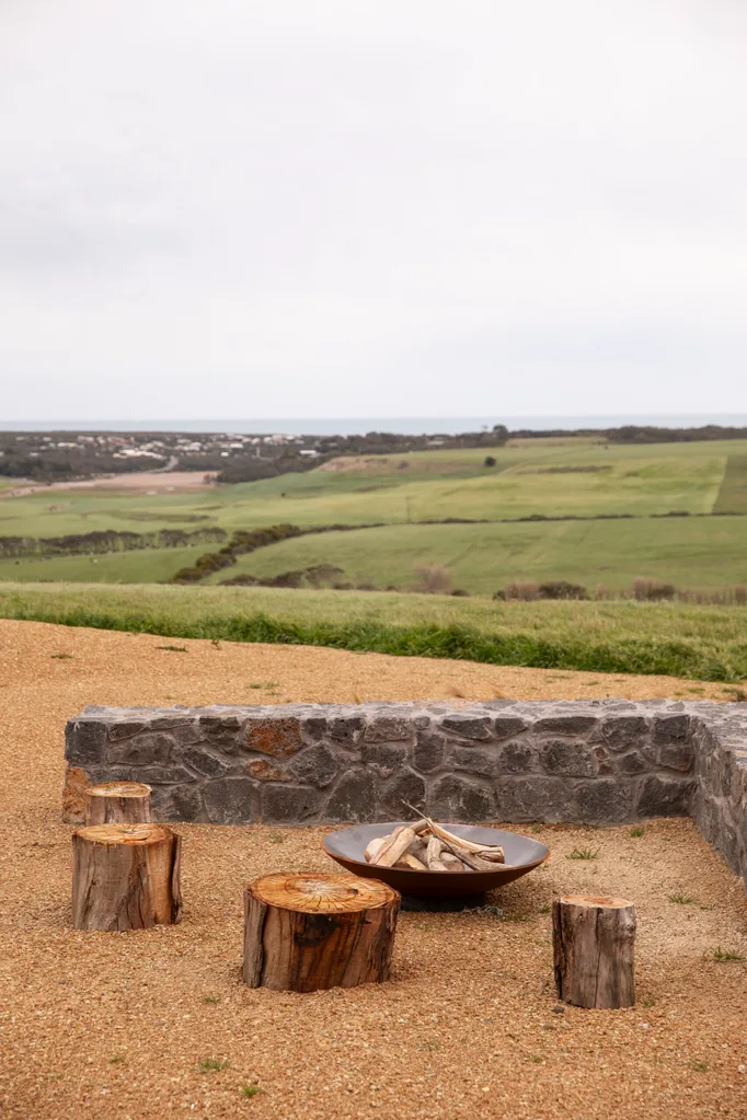 An outdoor firepit area with view over rolling hills to the ocean beyond.