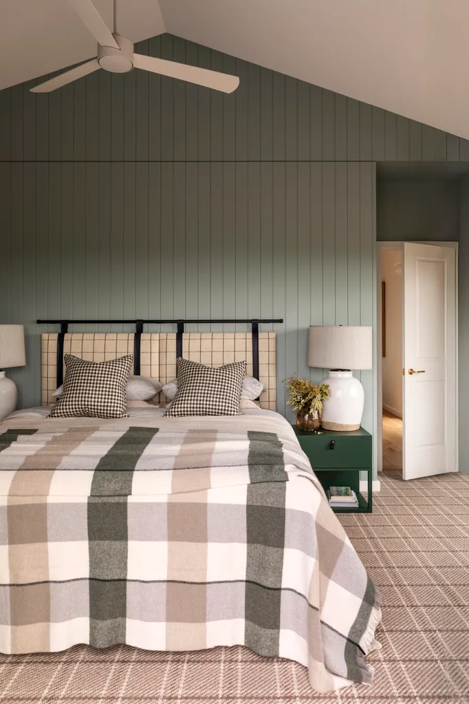 A country coastal bedroom with tongue-and-groove wall panelling and a pitched ceiling.