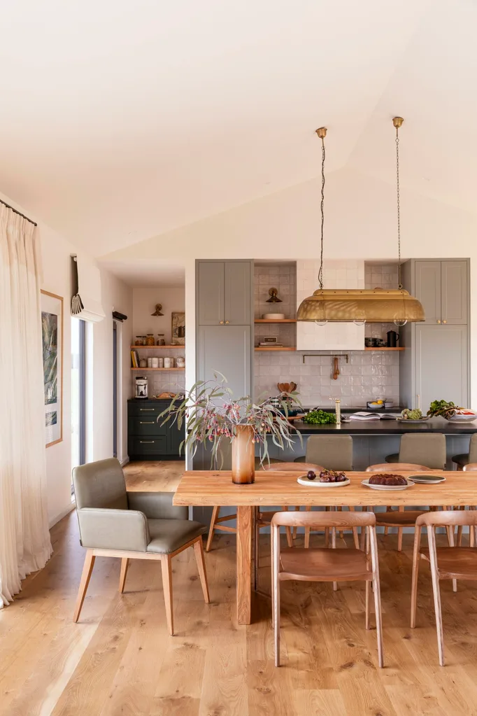 A bright, country-style kitchen and dining room with wooden floor and sage-coloured cabinetry.