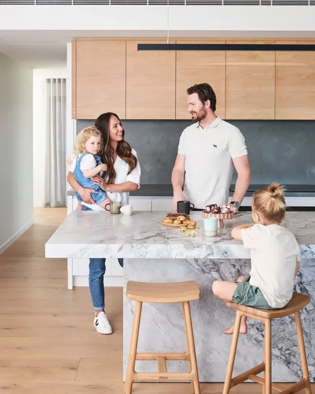 Afl Player and Geelong Cats star Patrick Dangerfield stands at the island benchtop of his kitchen with his wife Mardi and two children.