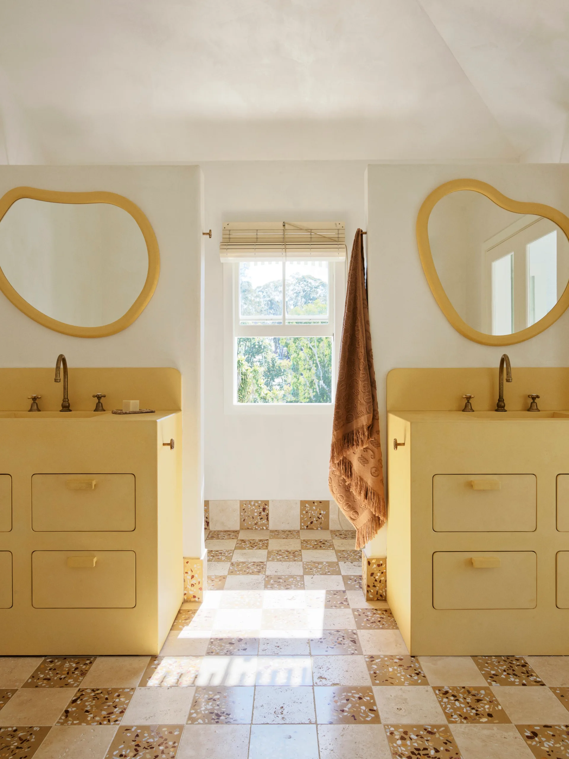 A yellow double bathroom with yellow vanities, mirrors and checkerboard flooring