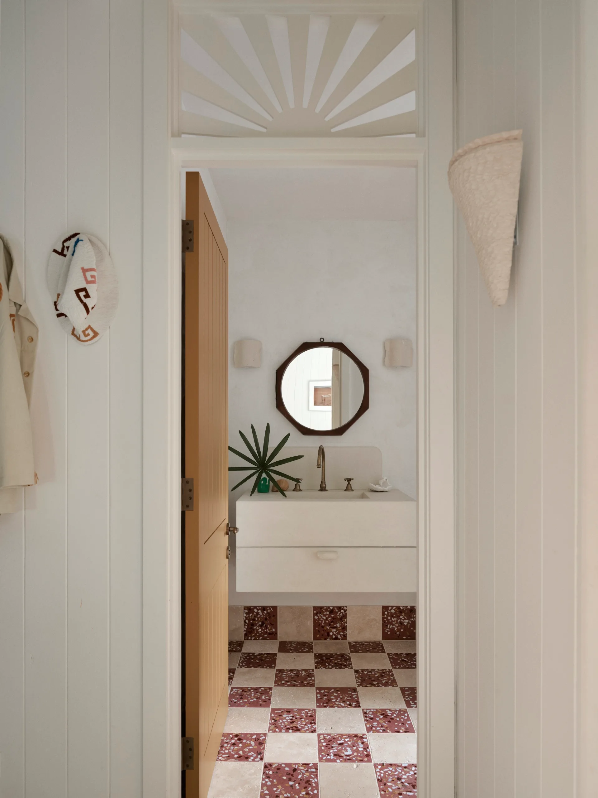 A bathroom with checkerboard tiles and a hexagonal mirror