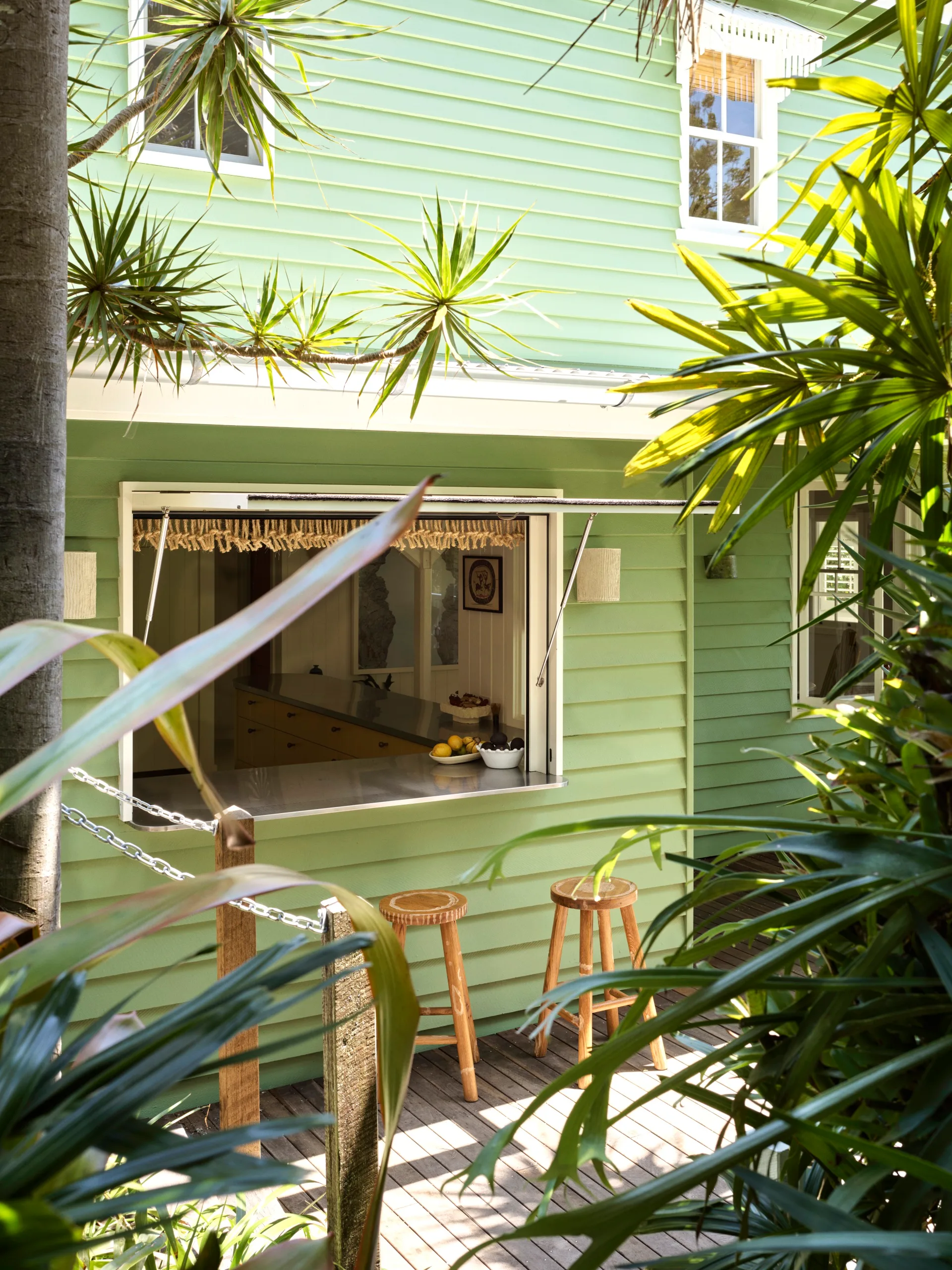 A green weatherboard home with a servery window