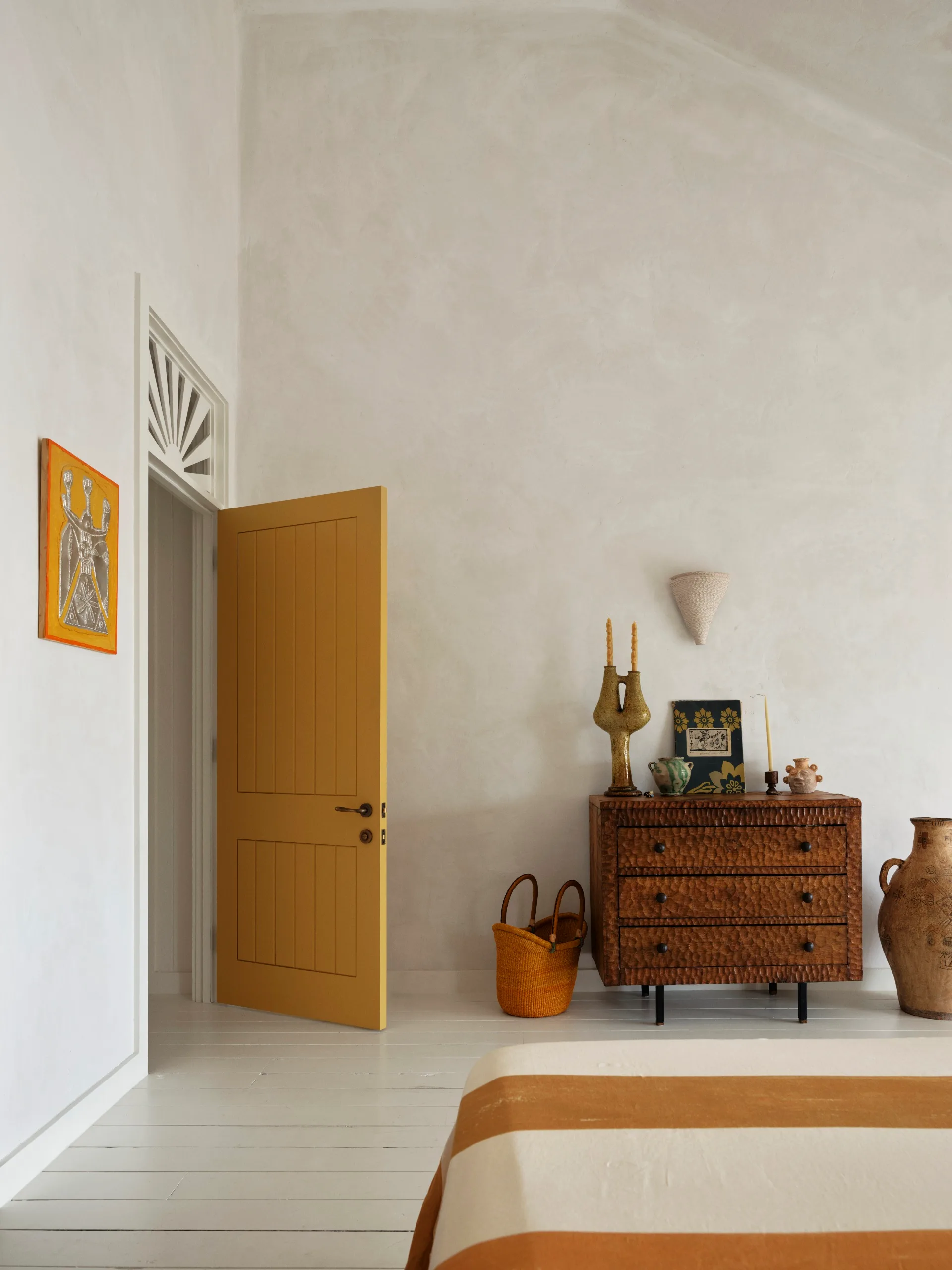 A bedroom with high ceilings, lime washed walls and antique furnishings