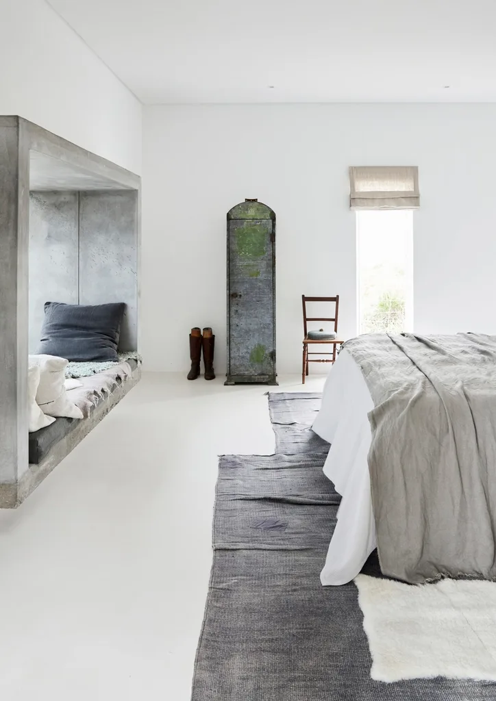 A white bedroom with a large concrete window seat and grey accents