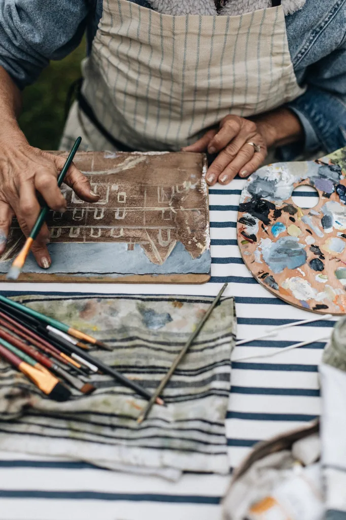 A table with a striped navy and white tablecloth covered in paint supplies.