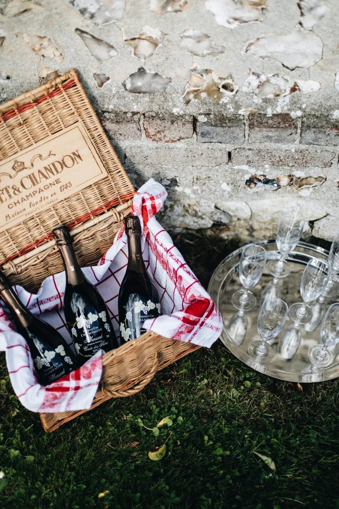 A Moet & Chandon basket is filled three bottles of champagne alongside a silver tray with champagne glasses.