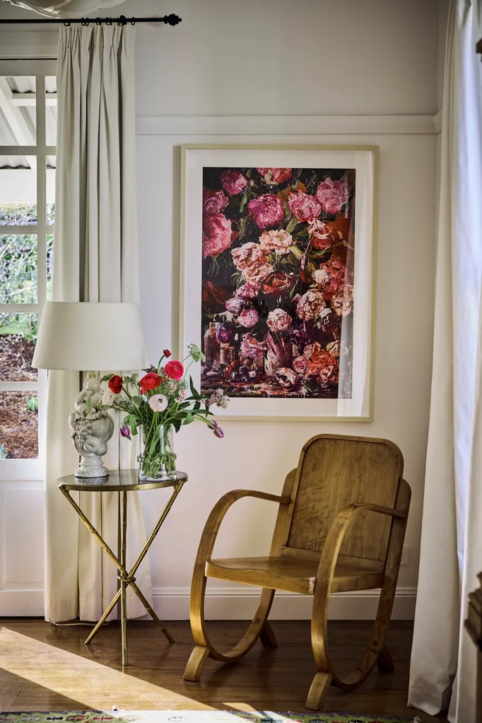 A sculptural arm chair beneath a floral framed print