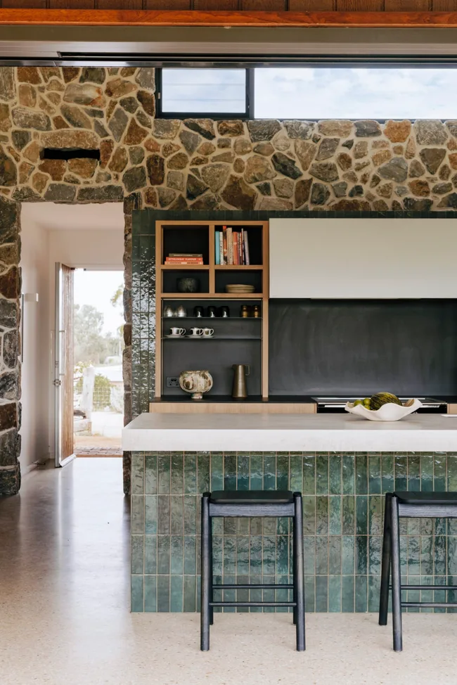 Kitchen with stone wall and green tile island bench