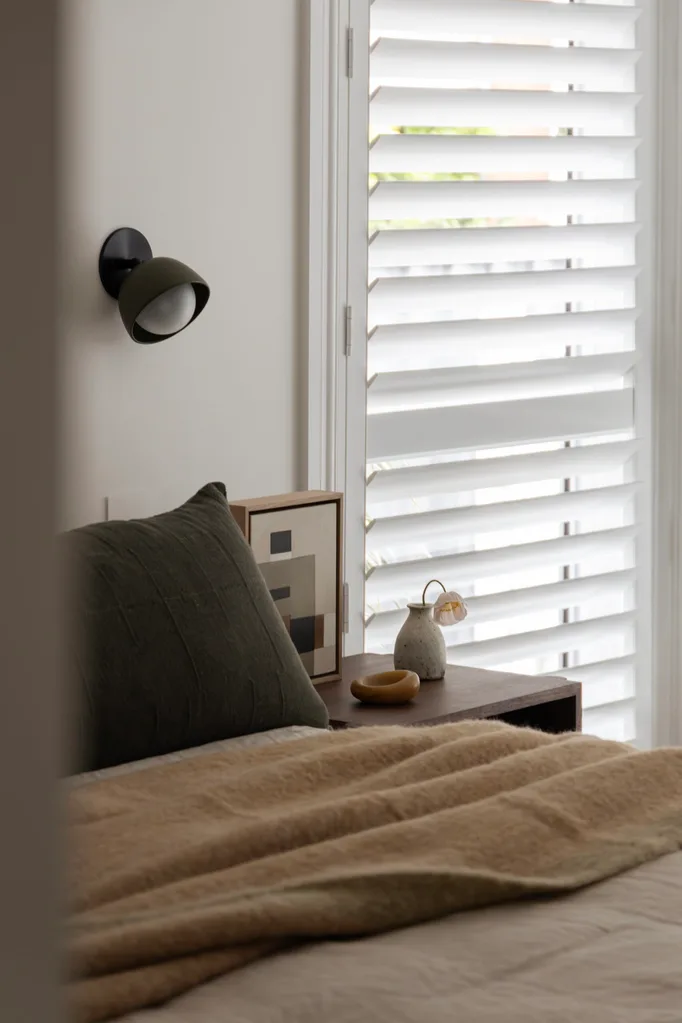 A neutral-toned bedroom with plantation shutters