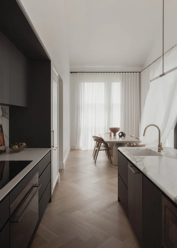 A modern kitchen and dining room with timber flooring and stone benchtops