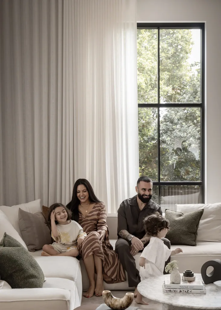 Matty and Sarah Fahd sat on a beige sofa with their two young children in their modern living room