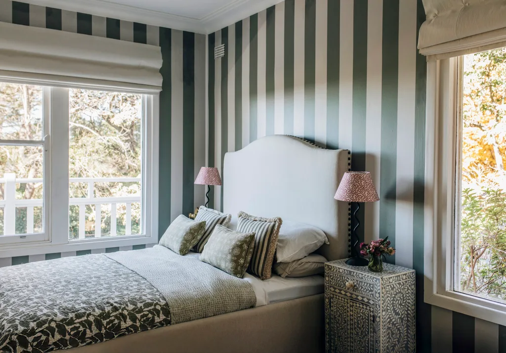 A bedroom with green and white striped wallpaper