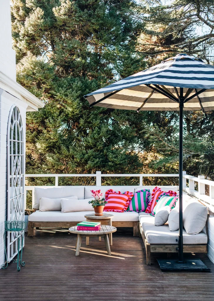 A treetop balcony with a corner lounge and a blue and white striped sun umbrella