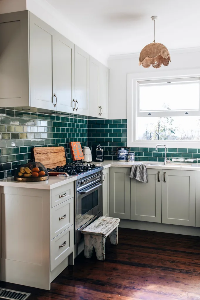 A country-style kitchen with soft greenish blue cupboards and a teal backsplash