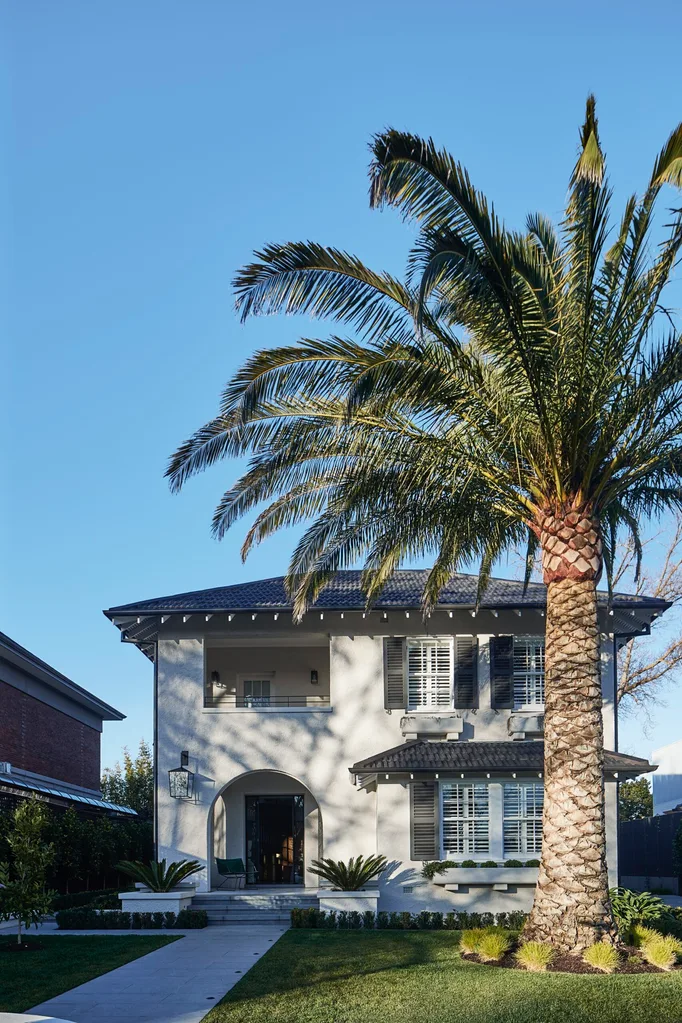 A Colonial Regency-style double-storey home behind a large palm tree