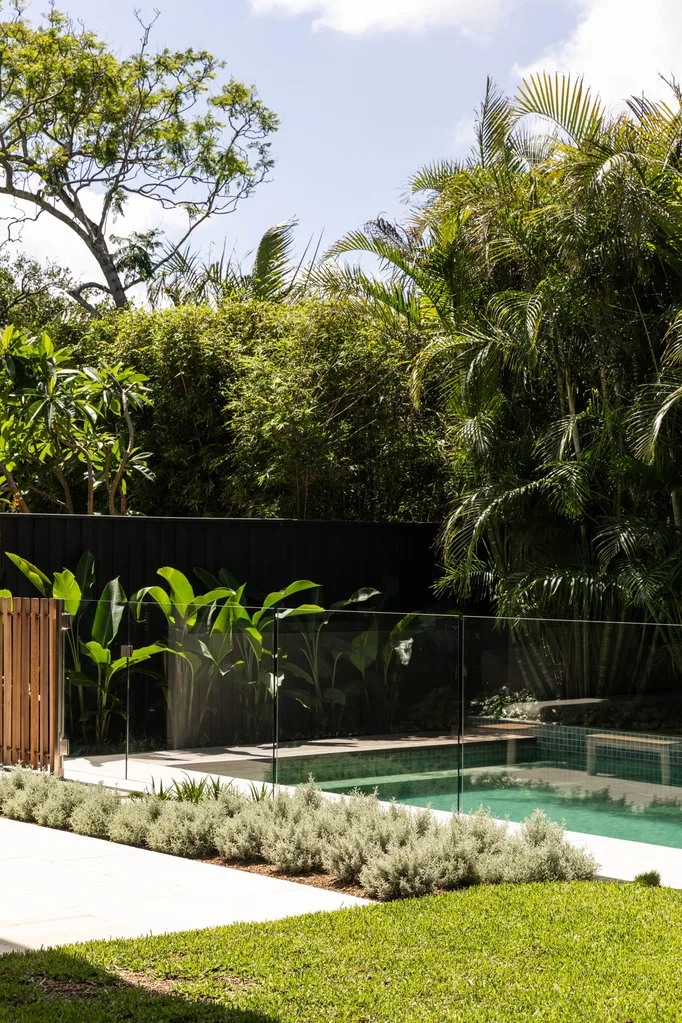 A garden with lawn and a swimming pool surrounded by palms