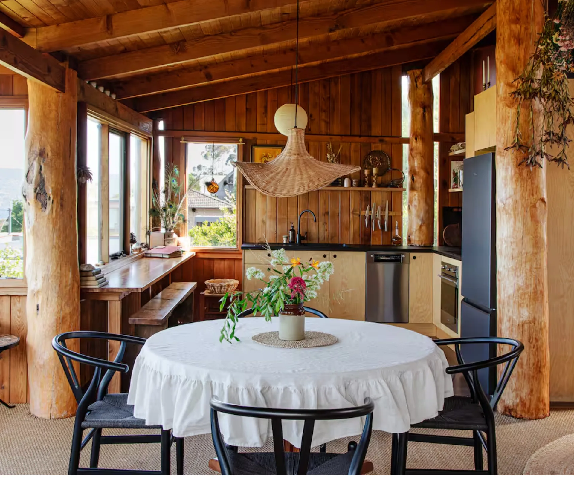 A timber-lined cabin with a dining area and kitchen overlooking the harbour