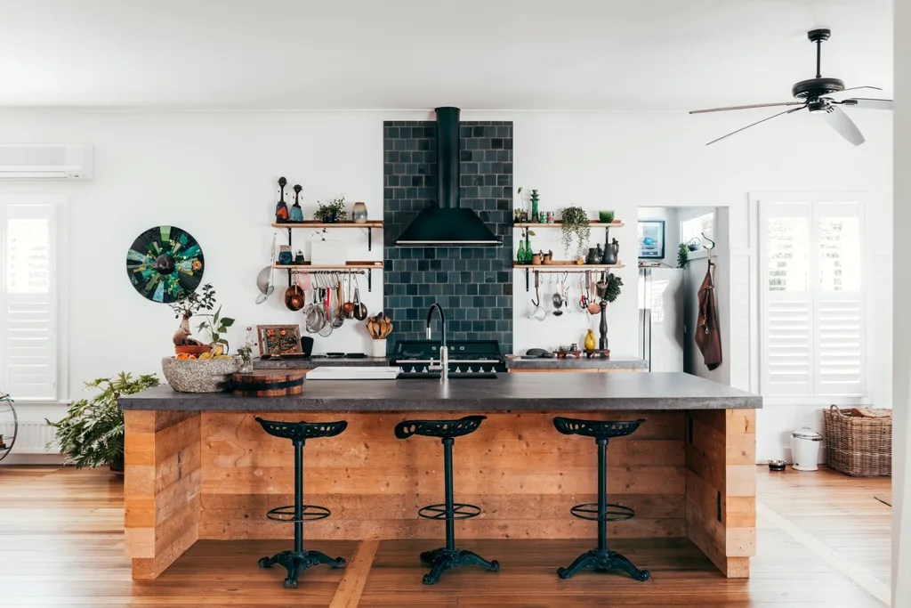 Kitchen with open shelving, timber island with granite benchtop, tractor-seat stools and blue-tiled splashback behind cooktop in a Grand Ridge House tour