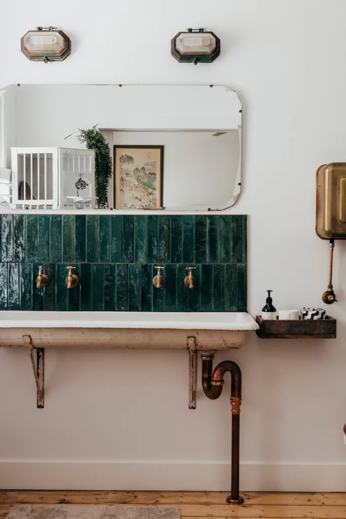 White bathroom with salvaged double sink, brass taps and green-tiled splashback in a Grand Ridge House tour