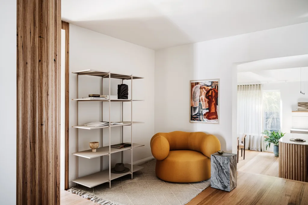 A sitting area with open shelving and a mustard-coloured armchair