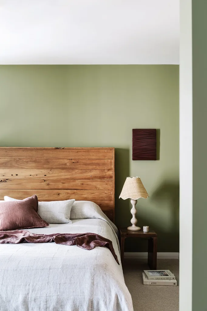 A green bedroom with a timber headboard
