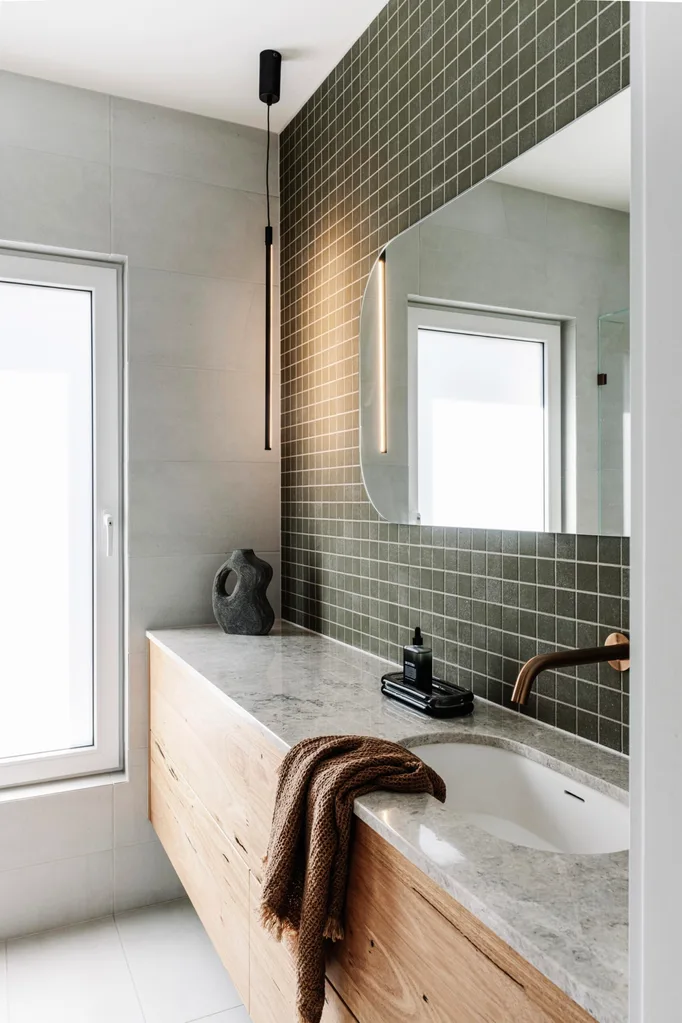 An ensuite with green square tiling and a stone benchtop