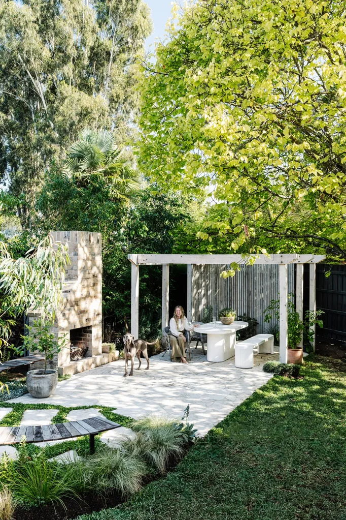 A shaded garden with an outdoor fireplace and alfresco dining area