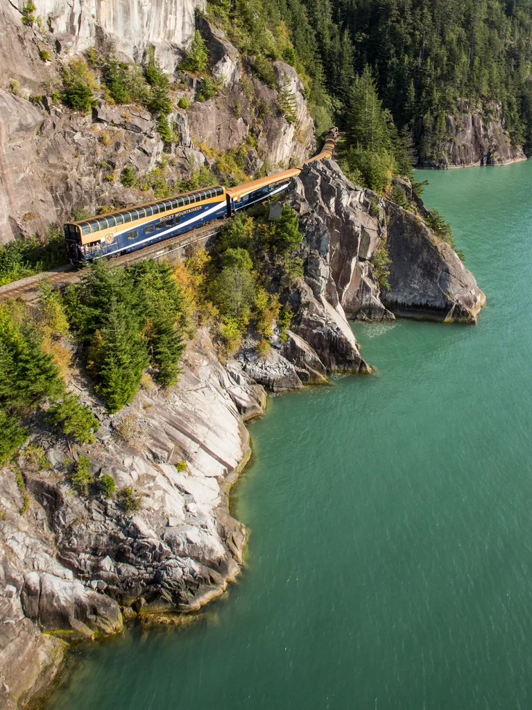 Train running along narrow track on edge of cliff with river below in Travel Canada Rocky Mountains