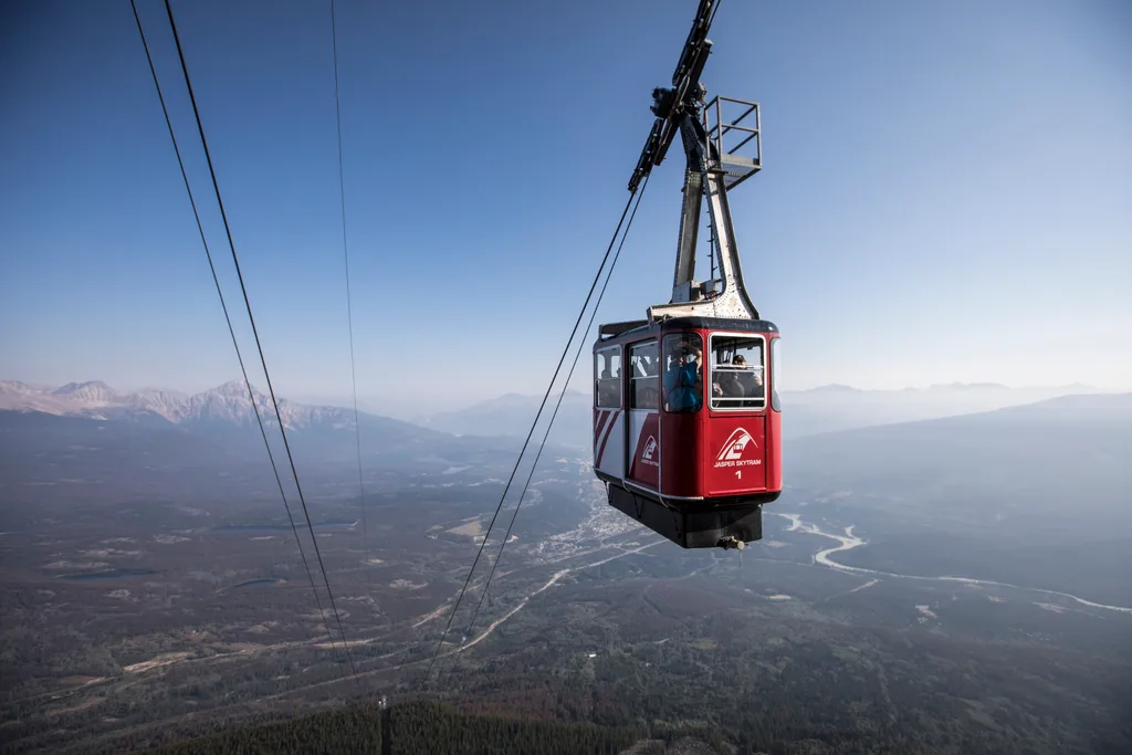 Cable car high in the air above wide valley with mountains
