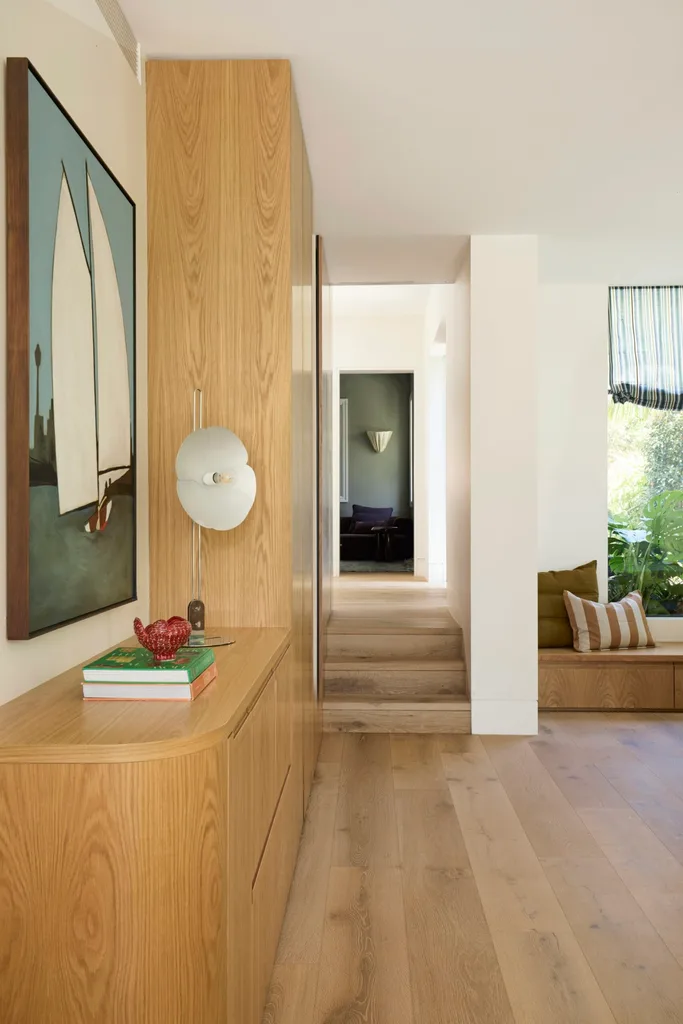 A hallway with a window seat and timber cabinetry