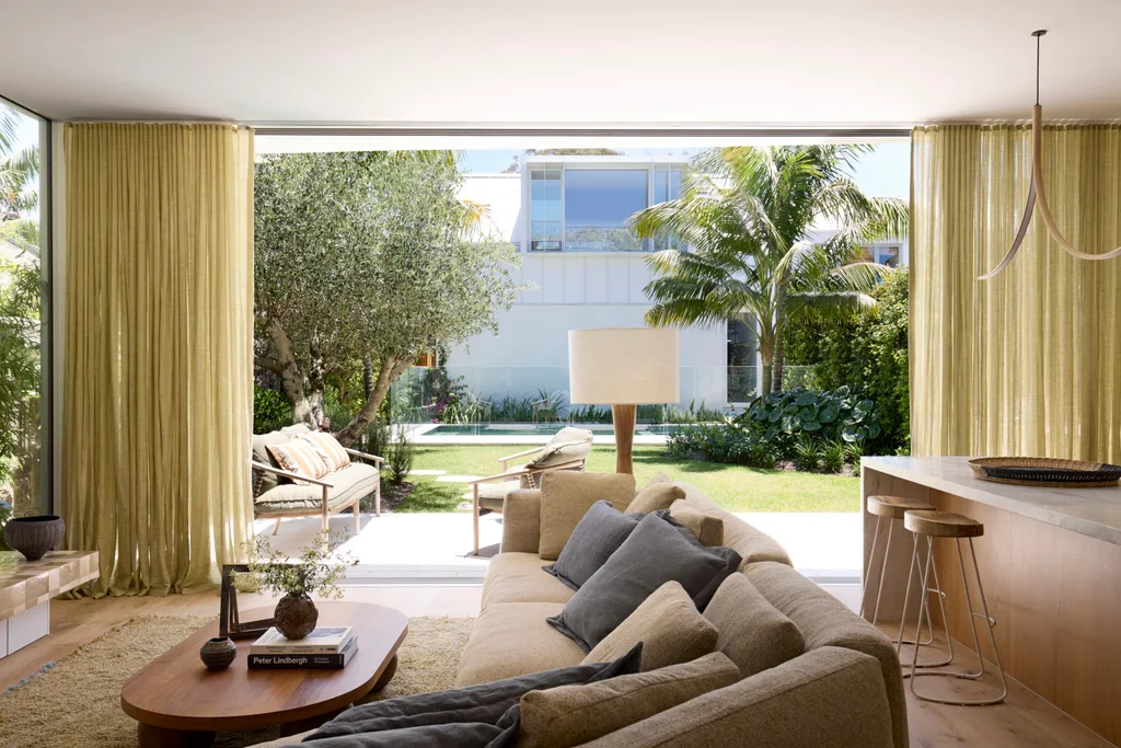 A contemporary lounge space with floor-to-ceiling doors opening out onto a sunny alfresco
