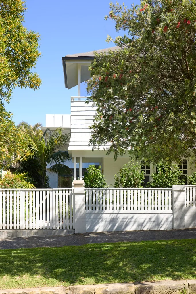A white double-storey home surrounded by trees