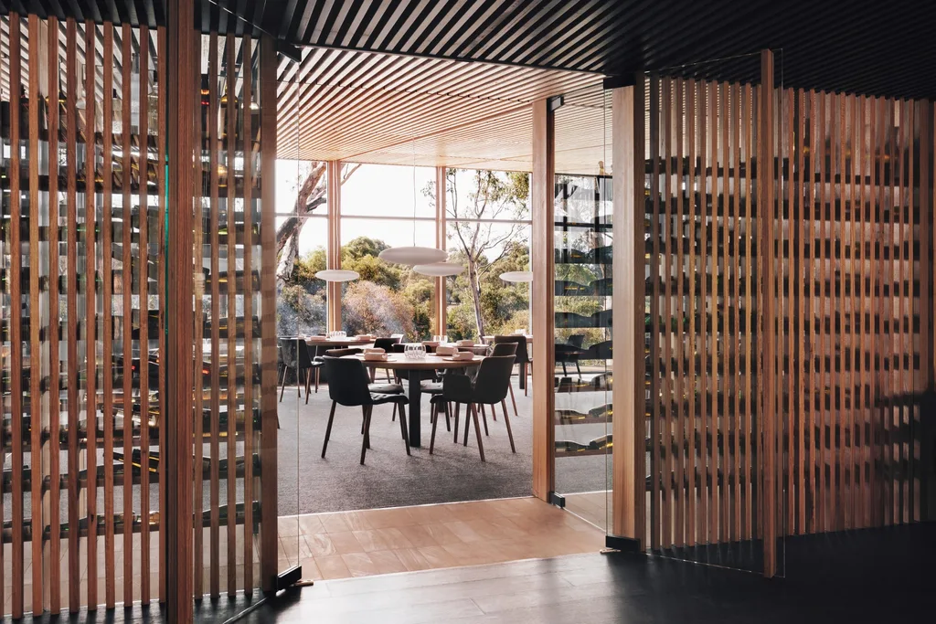 Wall of vertical timber slats with open door looking into glass-walled restaurant; view of trees in a travel story about a Grampians hotel