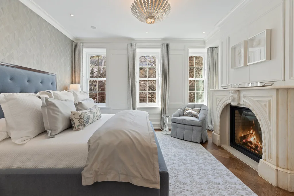 A luxurious bedroom with a stone fireplace and three sash windows