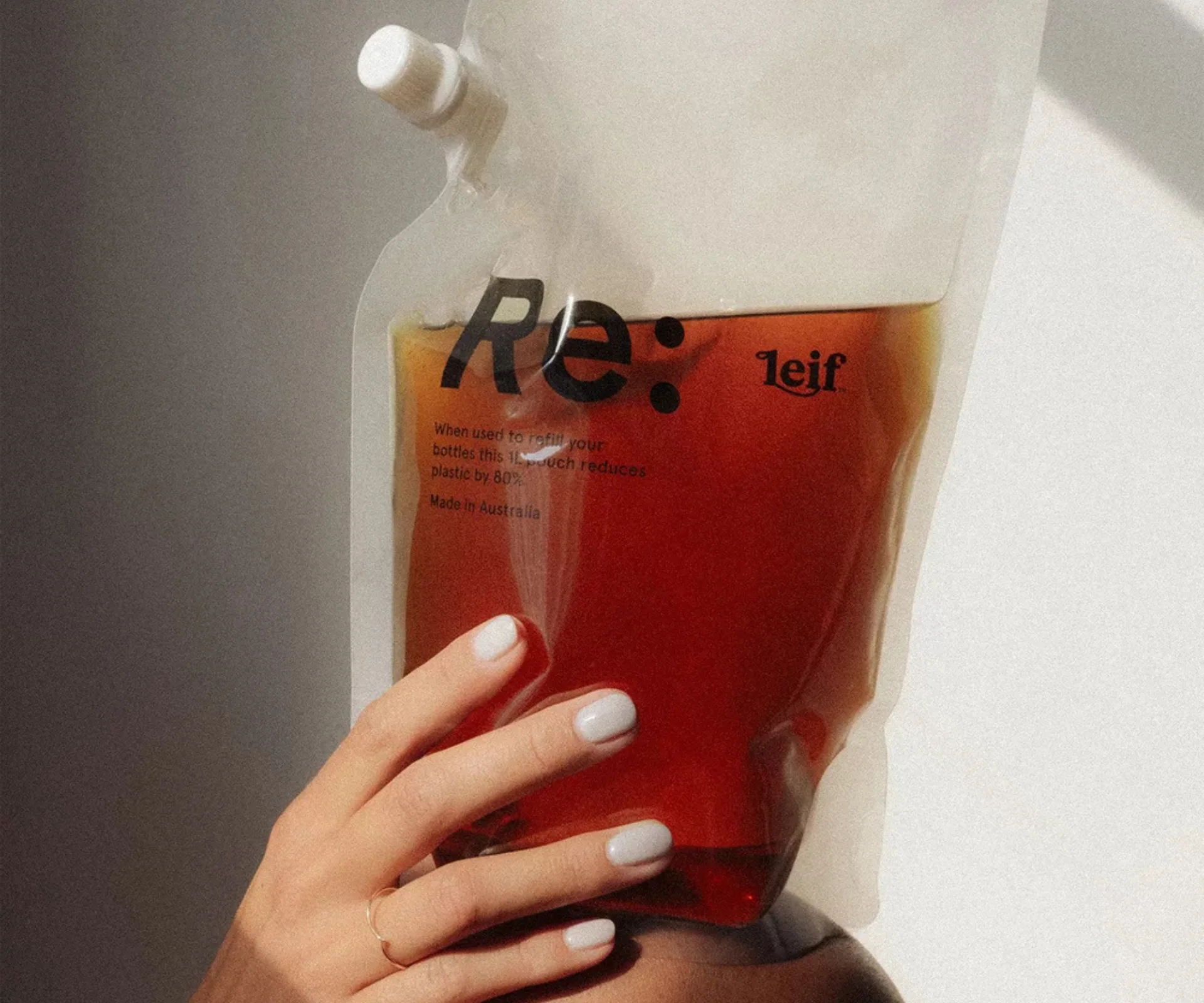 A large refillable soap being held in front of white wall