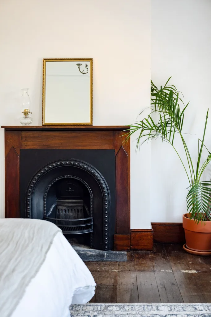 A country bedroom with original wooden floors and a restored fire place.