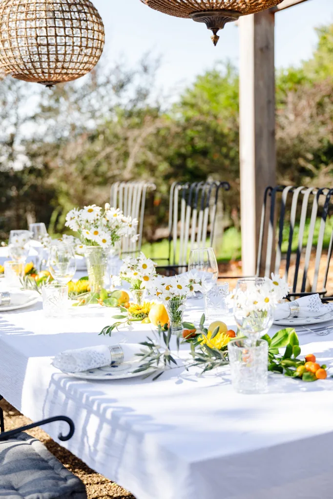 A table set with a white tablecloth, fresh flowers and citrus fruits.