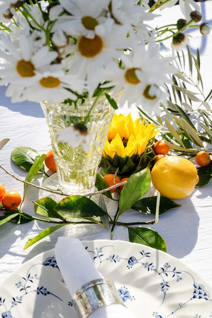 Details of a table laden with flowers and citrus fruits.