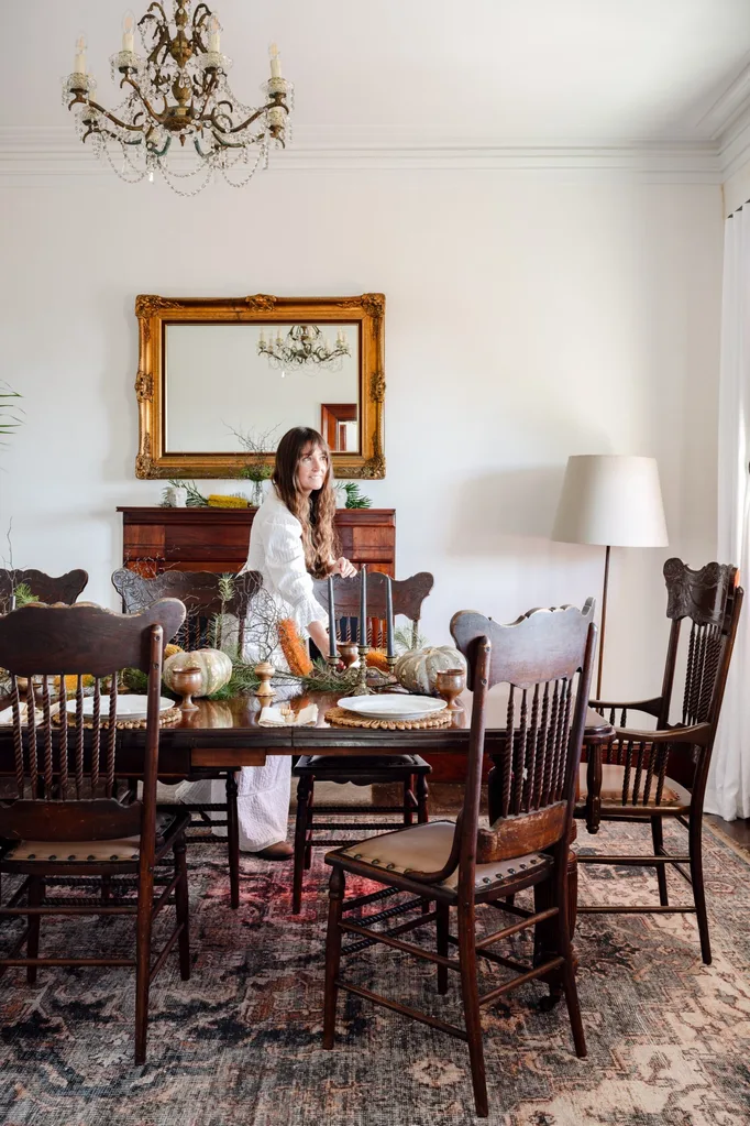 A woman in a white dress sets an antique table.