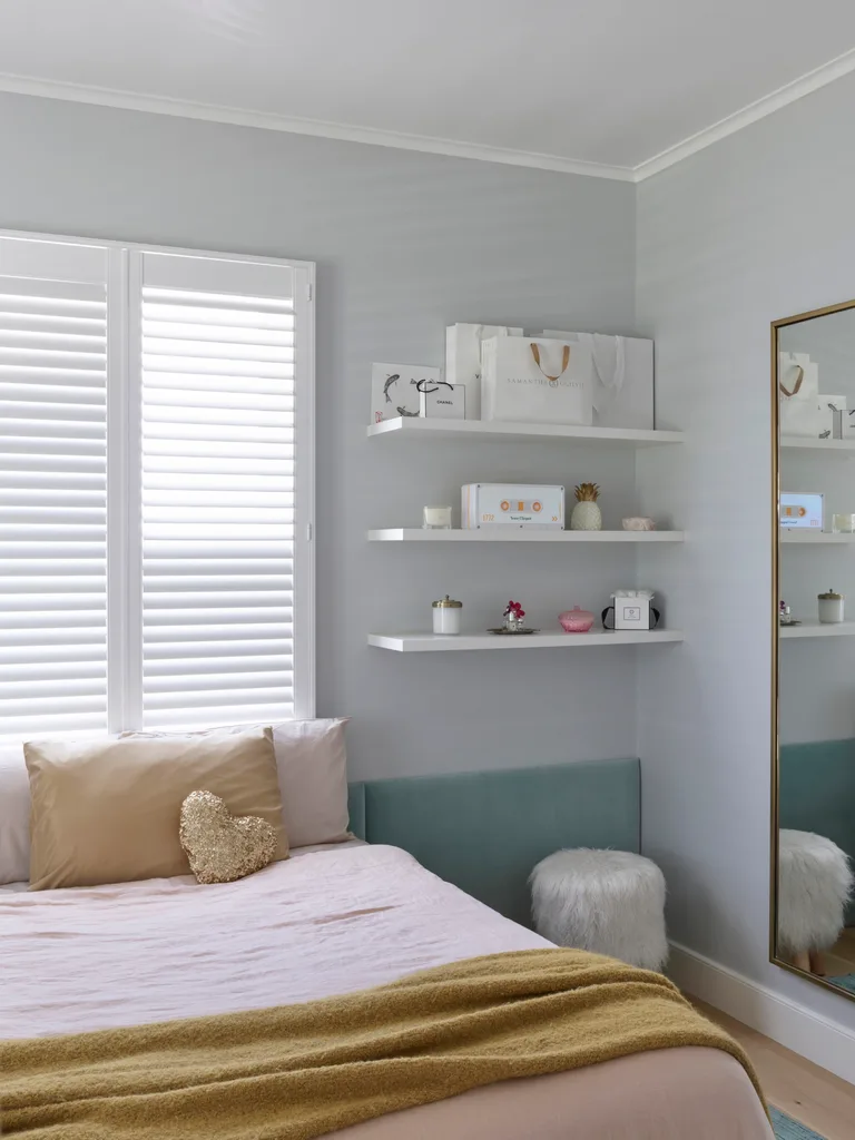 A child's bedroom with pink bedding and a custom teal bedhead in Oxford velvet.