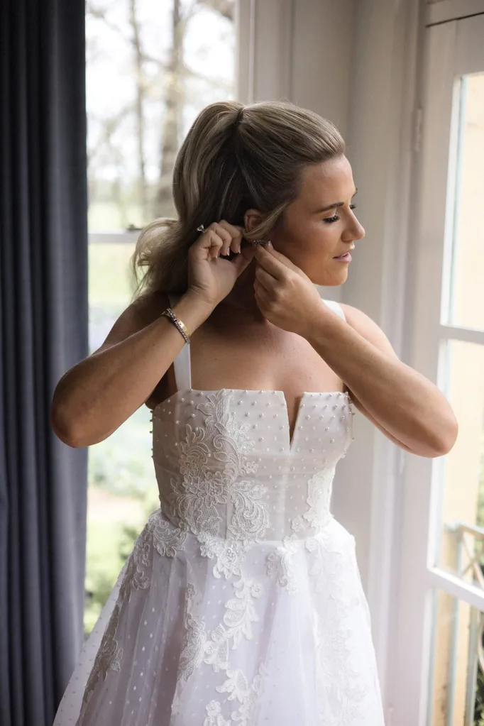 Sally putting on her earrings on her wedding day