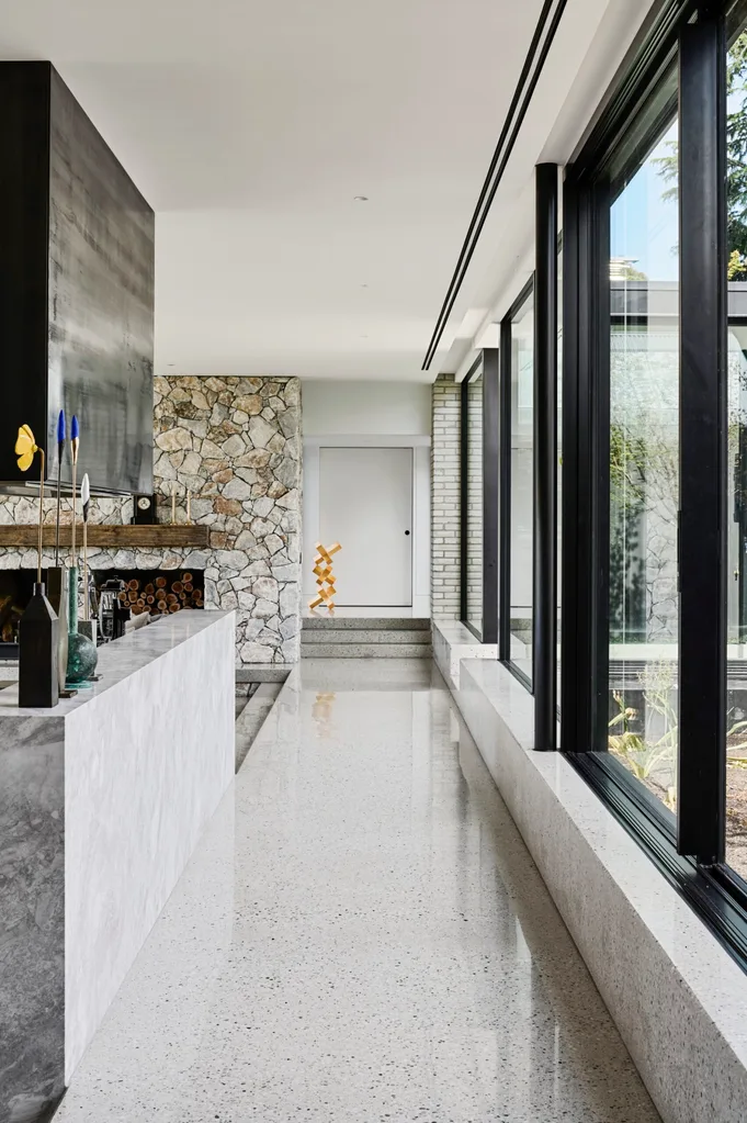 A sleek, modern hallway with polished concrete floors and large, black-framed windows.