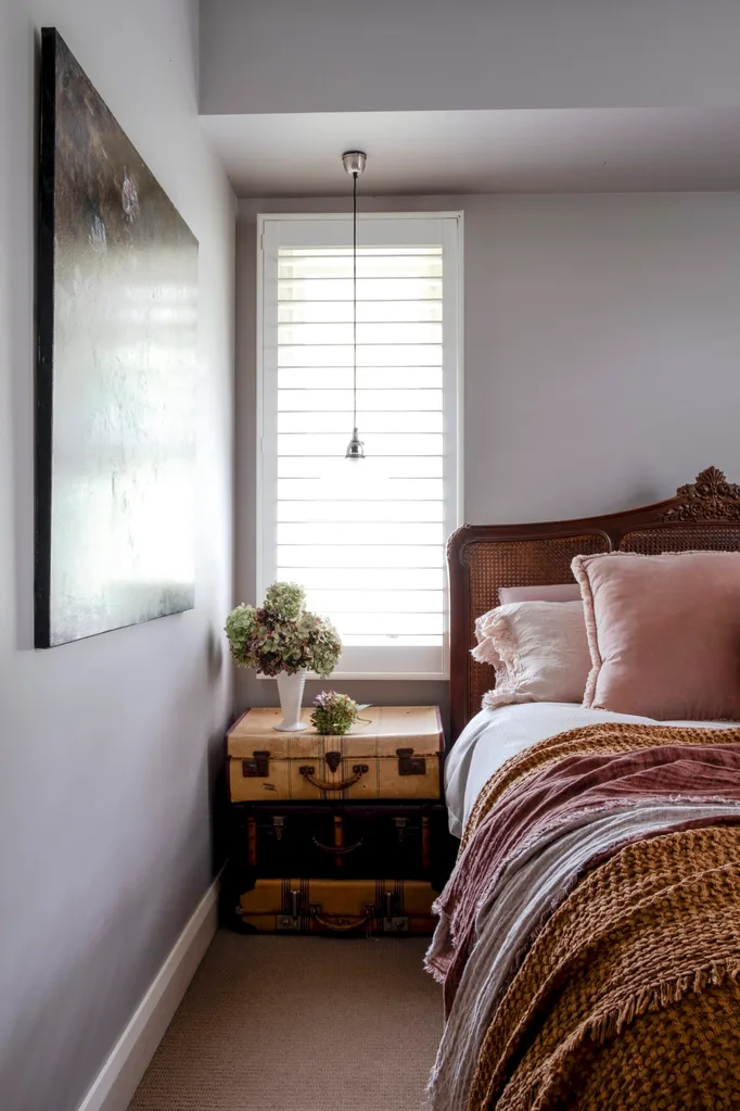 A bedroom with a stack of suitcases as a bedside table