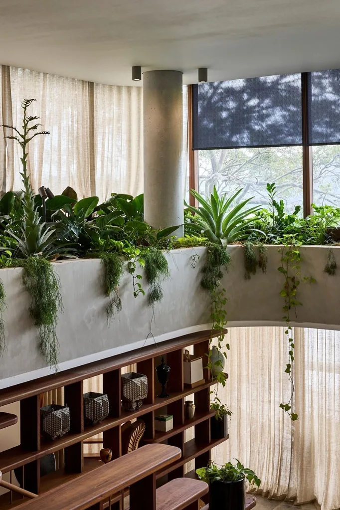 Open-plan living room with floor to ceiling windows with curtains and hanging garden