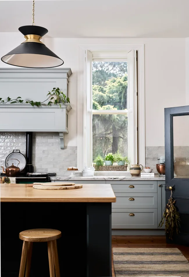 A kitchen with subway tile splashback, blue cabinetry and a timber island bench