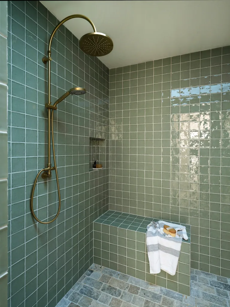 A green-tiled walk-in shower with a bench seat