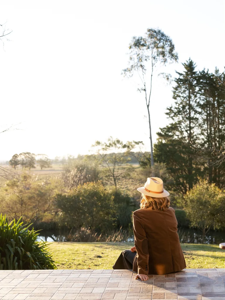 Interior designer Kate Hardy sitting on the steps of her home overlooking her acreage